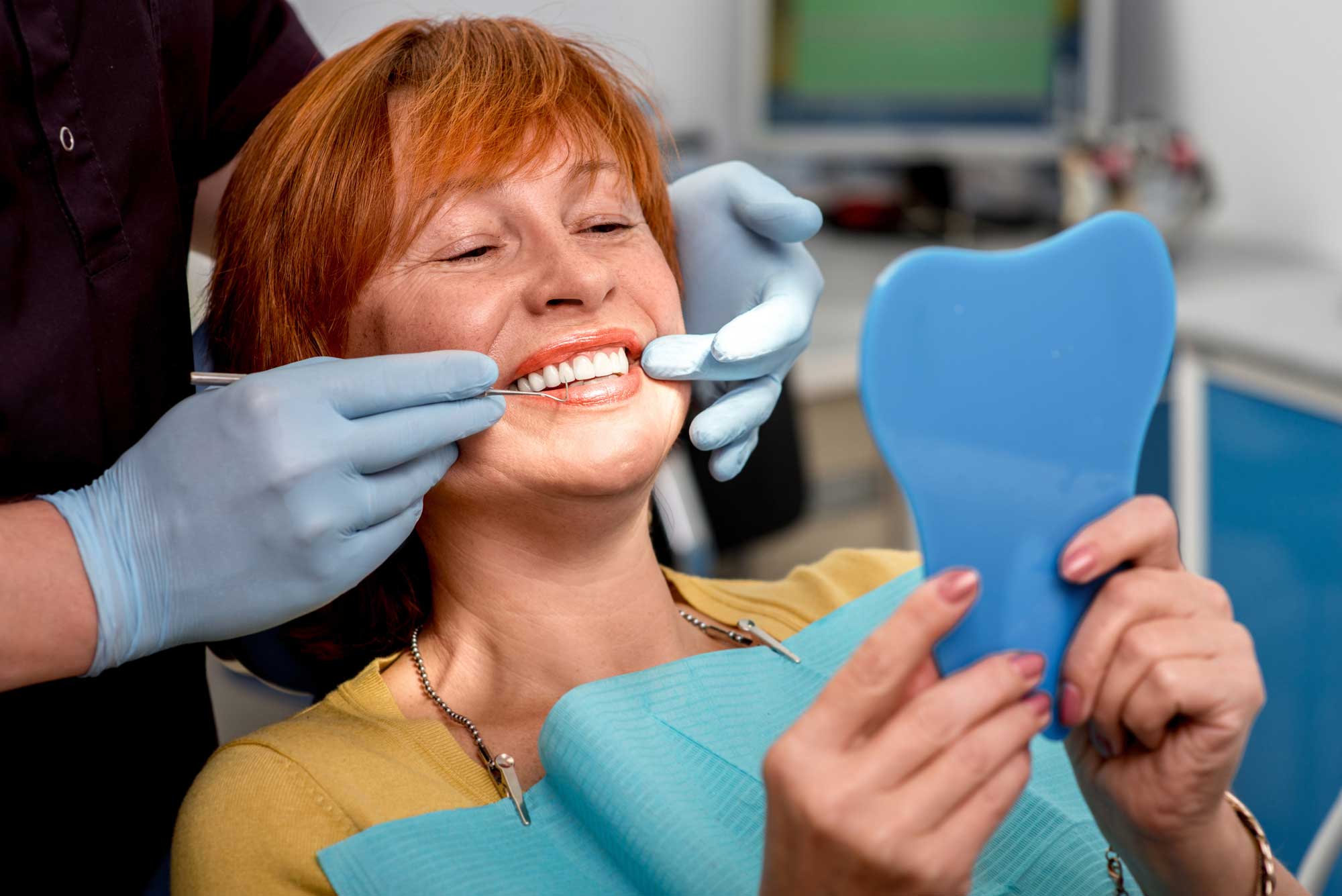 Implant Patient Looking in the Handheld Mirror